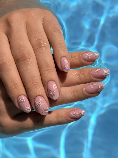 Nude Nägel mit feinen weißen Blüten am Pool